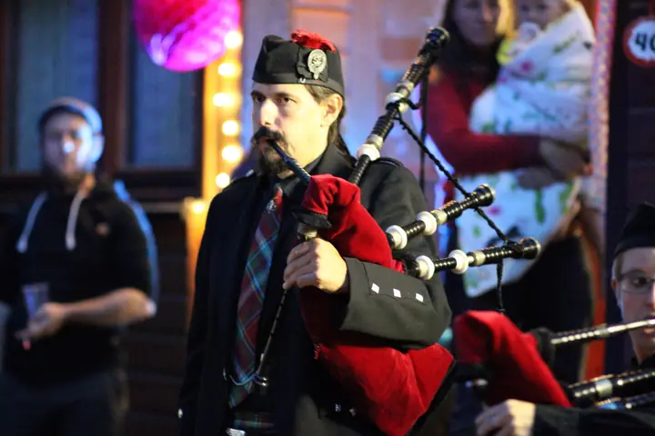 Dudelsackspieler der Pipes and Drums of Cherrytown mit rotem Dudelsack beim Abendauftritt